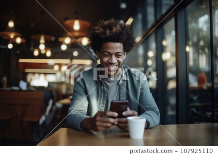adult african american man works in the office with a smartphone and coffee. positive man working on smartphone, modern technology adult african american man works in the office with a smartphone and coffee. positive man working on smartphone, modern technology 107925110