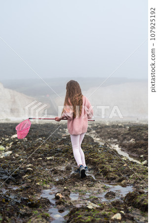 Little girl Eastbourne, East Sussex. Beach and sea in foggy morning Little girl Eastbourne, East Sussex. Beach and sea in foggy morning 107925192