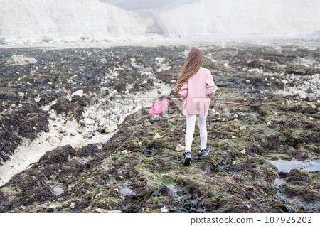 Little girl Eastbourne, East Sussex. Beach and sea in foggy morning Little girl Eastbourne, East Sussex. Beach and sea in foggy morning 107925202