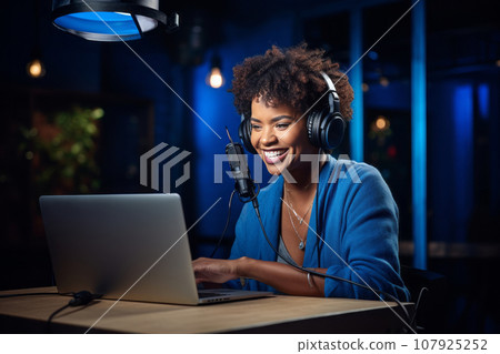 African American woman recording a blog in the studio, wearing headphones in front of a microphone, recording podcasts, blogging African American woman recording a blog in the studio, wearing headphones in front of a microphone, recording podcasts, blogging 107925252