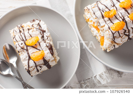 Swedish Budapest roll with hazelnut meringue and mandarins closeup on the plate. Horizontal top view 107926540