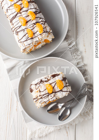 Classic gluten-free Budapest roll cake with mandarins closeup on the plate. Vertical top view 107926541