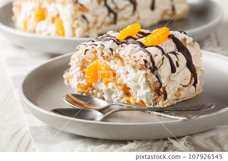 Gluten-free traditional Swedish dessert Budapest roll filled with whipped cream and tangerines close-up in a plate. Horizontal 107926545