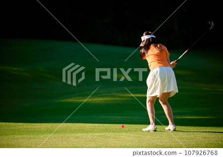 Woman hitting with a fairway wood Woman hitting with a fairway wood 107926768