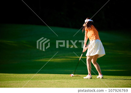 Woman hitting with a fairway wood Woman hitting with a fairway wood 107926769