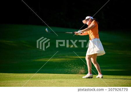 Woman hitting with a fairway wood Woman hitting with a fairway wood 107926770