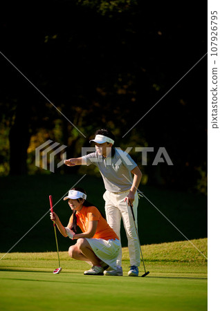 Couple reading the line on the green 107926795