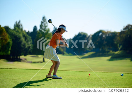 Woman hitting a tee shot 107926822
