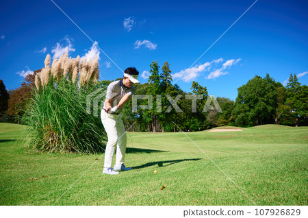 A man in his 40s playing golf under the blue sky 107926829
