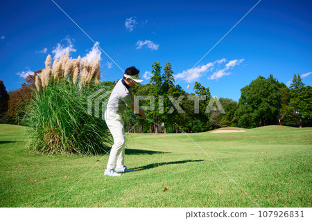 A man in his 40s playing golf under the blue sky 107926831