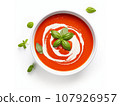Tomato soup puree in a bowl with cream and fresh basil leaves, isolated on white background. Top view 107926957