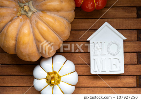 Cozy layout on a wooden background of slats with pumpkins, autumn leaves, a house and keys - autumn mood, Halloween, housing, relocation, mortgage, insurance. 107927250