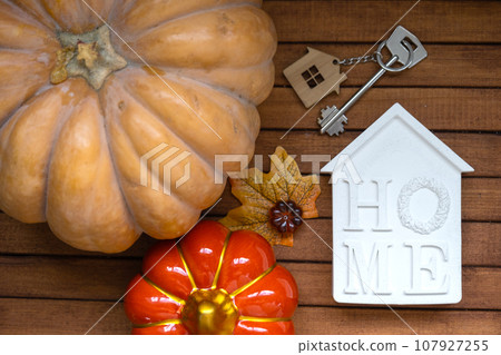 Cozy layout on a wooden background of slats with pumpkins, autumn leaves, a house and keys - autumn mood, Halloween, housing, relocation, mortgage, insurance. Cozy layout on a wooden background of slats with pumpkins, autumn leaves, a house and keys - autumn mood, Halloween, housing, relocation, mortgage, insurance. 107927255