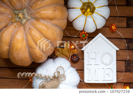 Cozy layout on a wooden background of slats with pumpkins, autumn leaves, a house and keys - autumn mood, Halloween, housing, relocation, mortgage, insurance. Cozy layout on a wooden background of slats with pumpkins, autumn leaves, a house and keys - autumn mood, Halloween, housing, relocation, mortgage, insurance. 107927256