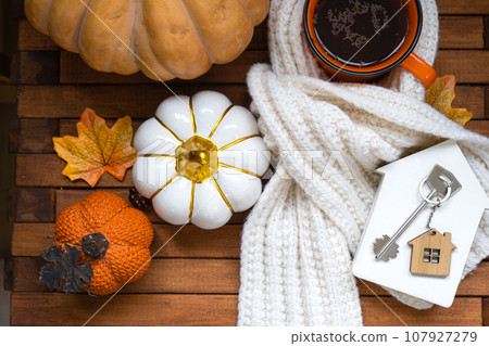 Cozy layout on a wooden background of slats with pumpkins, autumn leaves, a house and keys - autumn mood, Halloween, housing, relocation, mortgage, insurance. Cozy layout on a wooden background of slats with pumpkins, autumn leaves, a house and keys - autumn mood, Halloween, housing, relocation, mortgage, insurance. 107927279