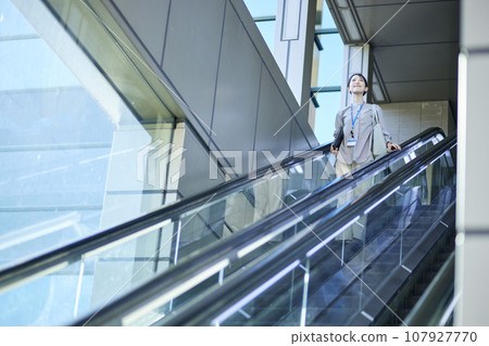 Japanese business woman riding an escalator 107927770
