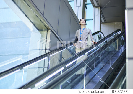 A young Japanese woman is using an escalator inside the train station. A young Japanese woman is using an escalator inside the train station. 107927771