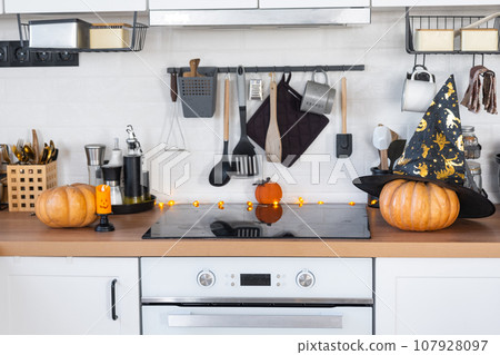 Decor of the white classic kitchen with pumpkins for Halloween and harvest. Autumn mood in the home interior, modern loft style. 107928097