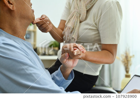 Cropped image of loving elderly couple holding hands while spending tome together at home 107928900