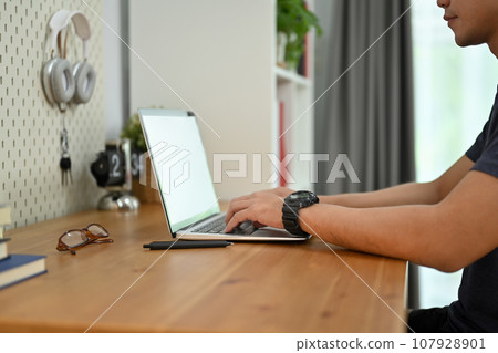 Cropped shot of man hands typing on laptop computer working online or browsing internet at home 107928901