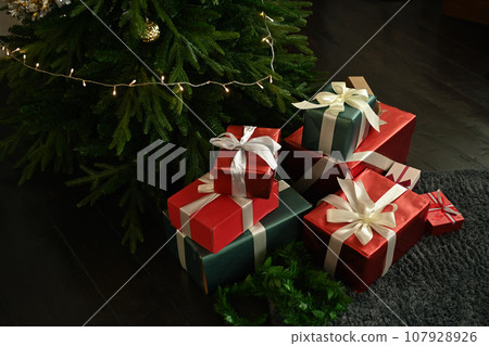 Pile of gift boxes on floor near decorated Christmas tree. Winter holiday celebration concept 107928926