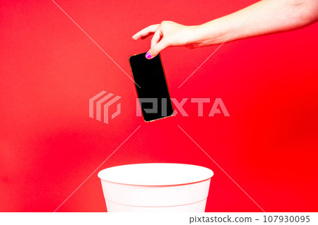 The smartphone is thrown into the trash for disposal and recycling 107930095