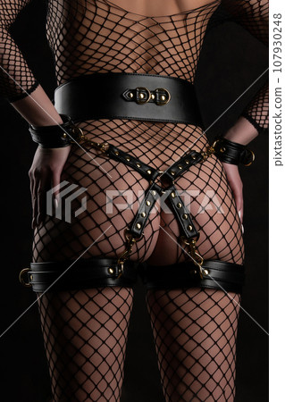 Beautiful woman in a full body mesh stands with her back in bondage set Beautiful woman in a full body mesh stands with her back in bondage set 107930248