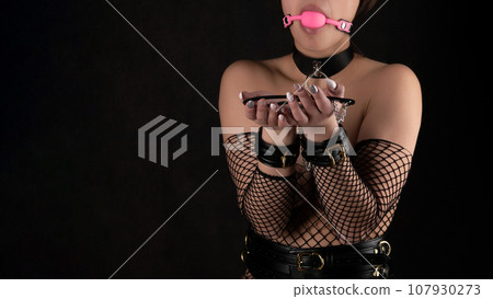 Beautiful woman in the role of a slave on a leash on black background Beautiful woman in the role of a slave on a leash on black background 107930273
