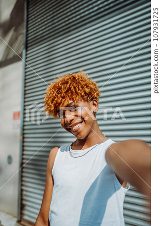Vertical view of young millennial african american guy making selfie portraits on mobile phone Vertical view of young millennial african american guy making selfie portraits on mobile phone 107931725