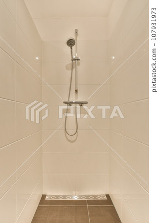a shower with white tiles on the walls and brown wood flooring in a modern style bathroom area that is clean and ready for a shower with white tiles on the walls and brown wood flooring in a modern style bathroom area that is clean and ready for 107931973