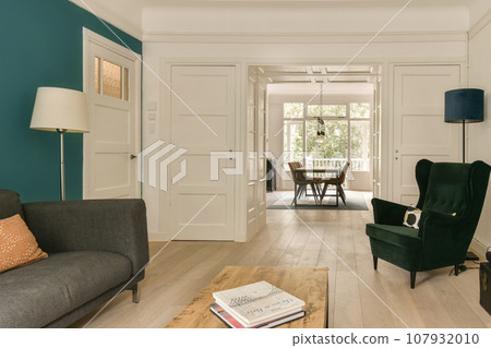 a living room with blue walls and white trim on the walls, wood flooring and green chair in the middle a living room with blue walls and white trim on the walls, wood flooring and green chair in the middle 107932010