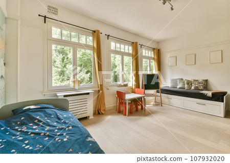 a child's room with a bed, desk, and tv in the corner of the room on the wall 107932020