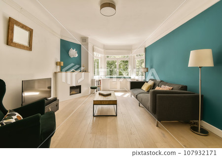 a living room with teal blue walls and white trim on the walls, hardwood flooring is light wood a living room with teal blue walls and white trim on the walls, hardwood flooring is light wood 107932171