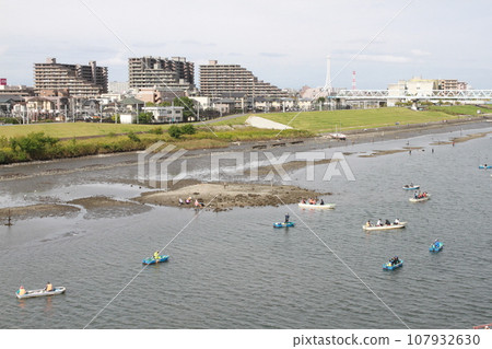 Tidal flats revealed by low tide and people enjoying fishing on boats (Edogawa) 107932630
