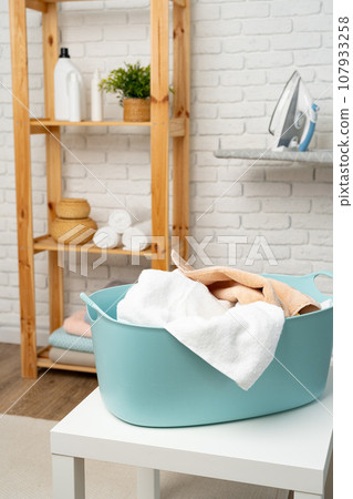 Blue plastic laundry basket in a bathroom 107933258