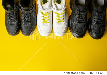 Several pairs of fashion trendy sport shoes on yellow background 107933320