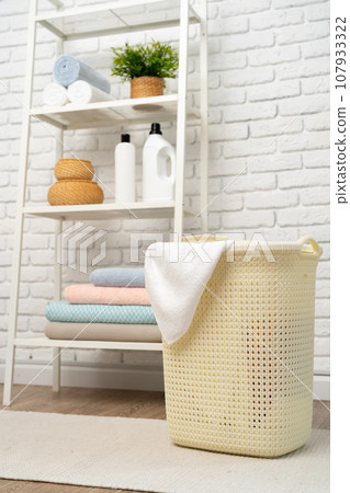 Beige plastic basket for laundry in a room Beige plastic basket for laundry in a room 107933322