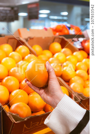 hand taking grapefruit from grocery store shelf hand taking grapefruit from grocery store shelf 107933542