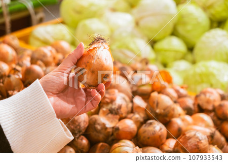 hand taking onion from grocery store shelf hand taking onion from grocery store shelf 107933543