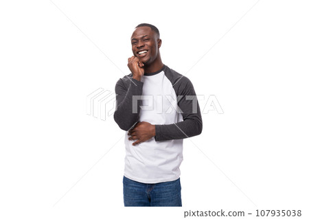 young well-groomed African guy dressed in a black-and-white sweatshirt and jeans in the studio on a 107935038