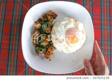 stir fried pork with basil and rice , sunny side up egg or stir fried bacon with basil 107935236