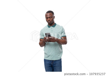 young cute american guy dressed in a mint t-shirt uses a smartphone for social networks young cute american guy dressed in a mint t-shirt uses a smartphone for social networks 107935237