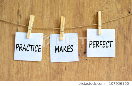 Practice makes perfect symbol. Concept words Practice makes perfect on beautiful white paper on clothespin. Beautiful wooden background. Business practice makes perfect concept. Copy space. 107936590