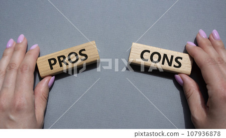 Pros vs Cons symbol. Concept word Pros vs Cons on wooden blocks. Businessman hand. Beautiful grey background. Business and Pros vs Cons concept. Copy space 107936878