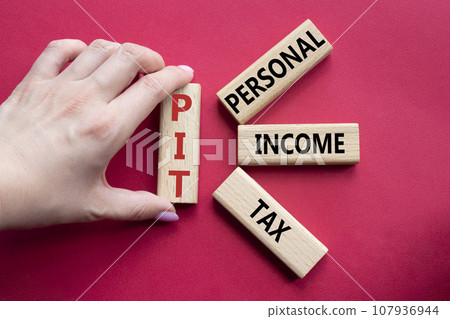 PIT - Personal Income Tax symbol. Wooden cubes with words PIT. Businessman hand. Beautiful red background. Business and PIT concept. Copy space. PIT - Personal Income Tax symbol. Wooden cubes with words PIT. Businessman hand. Beautiful red background. Business and PIT concept. Copy space. 107936944