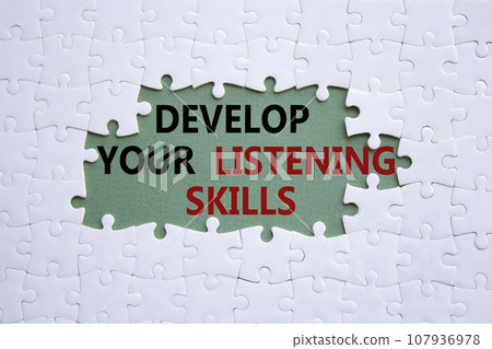 Listening skills symbol. Concept word Develop active listening skills on white puzzle. Beautiful grey green background. Business and Develop active listening skills concept. Copy space 107936978