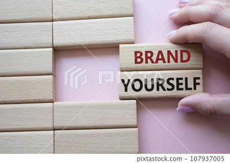 Brand yourself symbol. Concept word Brand yourself on wooden blocks. Businessman hand. Beautiful pink background. Business and Brand yourself concept. Copy space Brand yourself symbol. Concept word Brand yourself on wooden blocks. Businessman hand. Beautiful pink background. Business and Brand yourself concept. Copy space 107937005