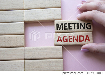 Meeting agenda symbol. Concept word Meeting agenda on wooden blocks. Businessman hand. Beautiful pink background. Business and Meeting agenda concept. Copy space Meeting agenda symbol. Concept word Meeting agenda on wooden blocks. Businessman hand. Beautiful pink background. Business and Meeting agenda concept. Copy space 107937009