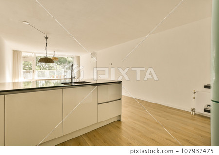 a kitchen with white cabinets and black counter tops on the island in front of the sink is open to the living room a kitchen with white cabinets and black counter tops on the island in front of the sink is open to the living room 107937475