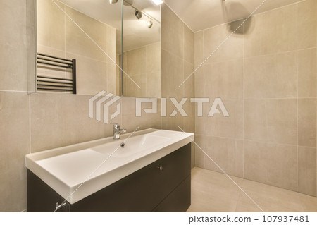 a bathroom with a sink, mirror and towel rack on the wall next to the bathtub is white tile a bathroom with a sink, mirror and towel rack on the wall next to the bathtub is white tile 107937481